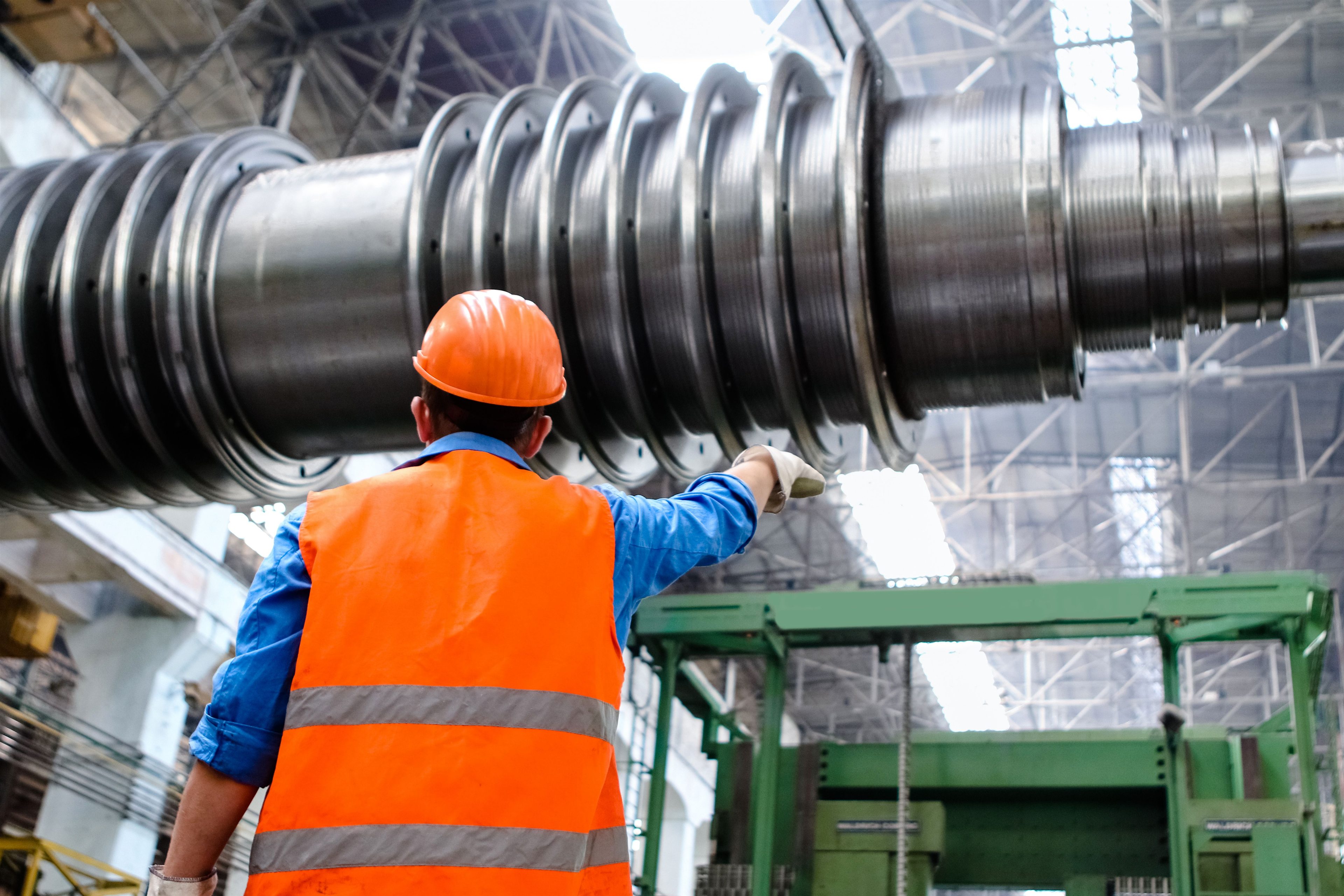 Operario con chaleco naranja frente a un rotor de turbina